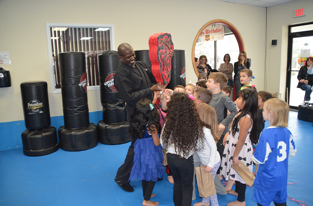 Piñata at karate birthday party Kids at karate birthday party are surrounding karate master who is holding a Piñata