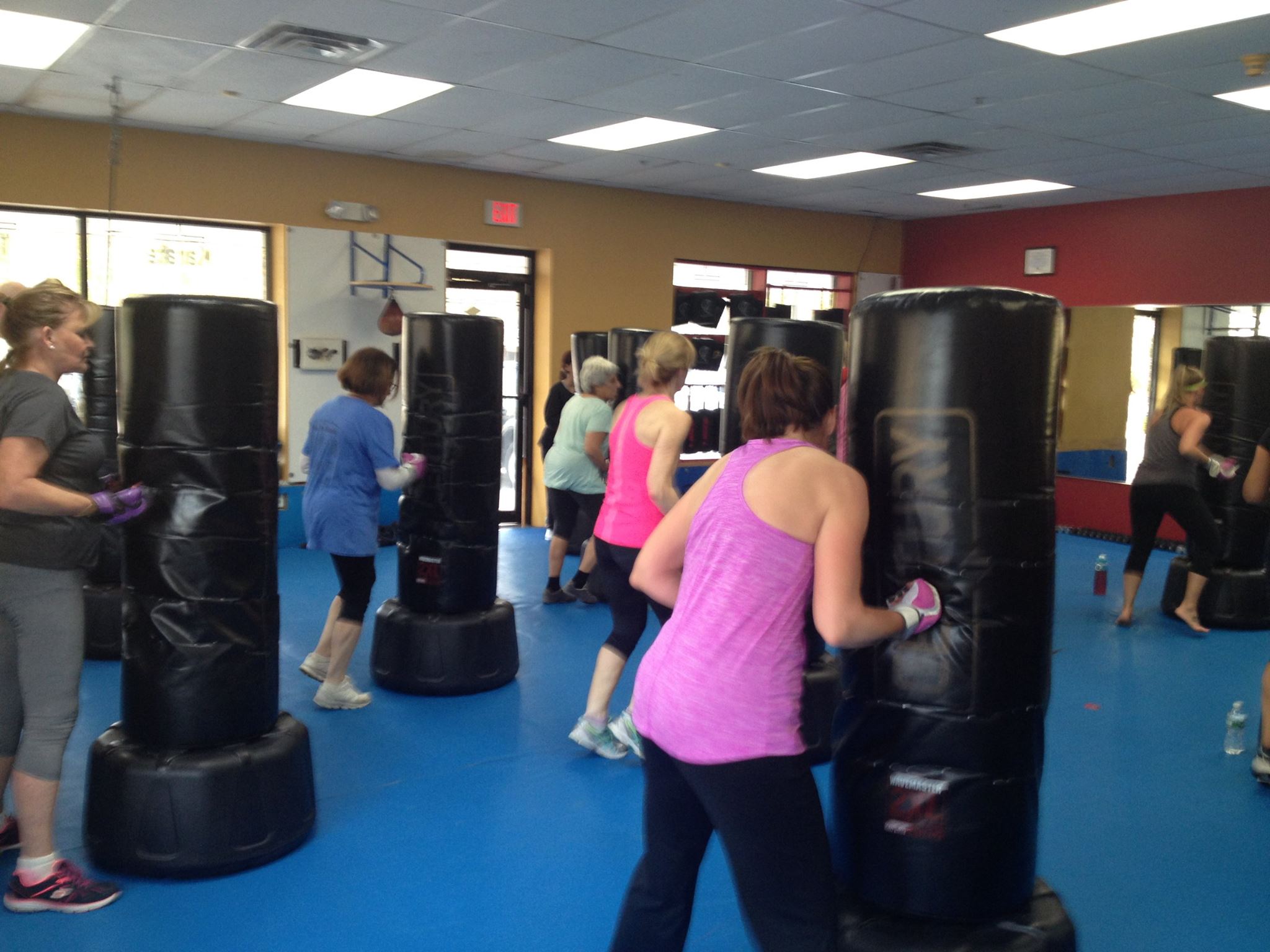 Fitness Kickboxing Women uppercutting the bags Fitness Kickboxing Women in class uppercutting the bag